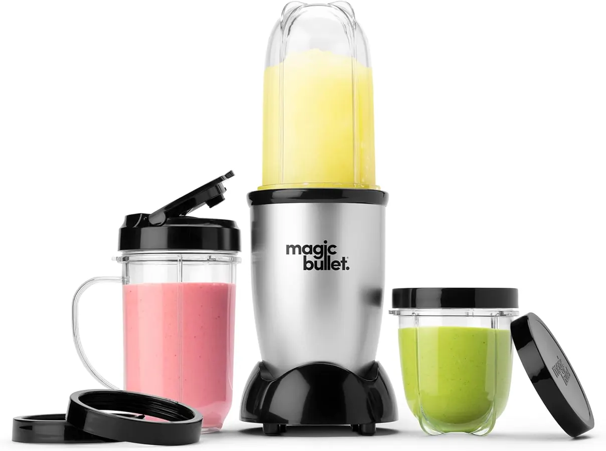 Hands layering spinach leaves into a Magic Bullet blending cup before adding frozen mango chunks