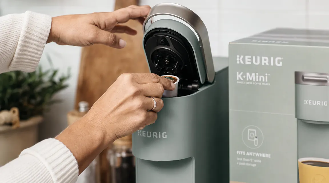 Hand inserting a K-Cup pod into the Keurig K-Mini brew chamber